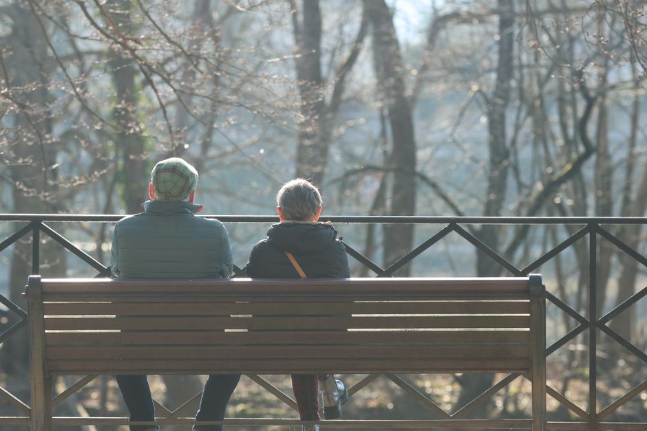 Senior couple enjoys a peaceful moment on a bench during a sunny autumn day in the park.