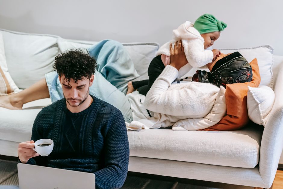 High angle of loving African American mom caressing girl while dad drinking coffee and watching netbook at home